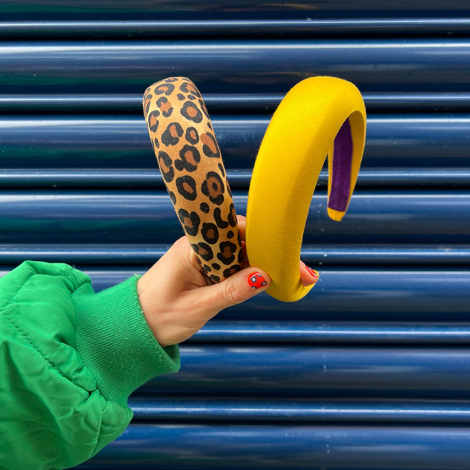 good manners style two headbands yellow and leopard held up in front of blue shutters